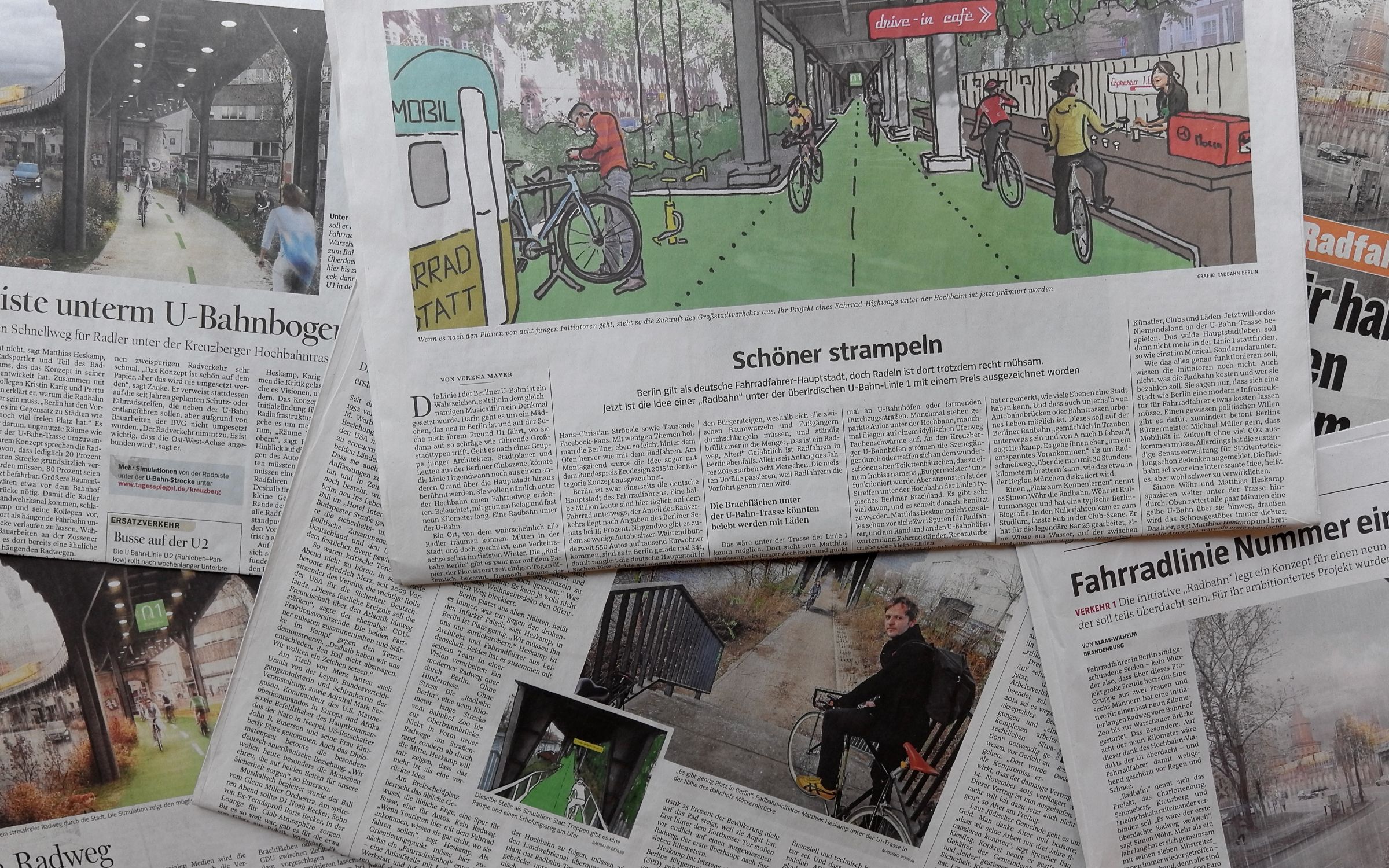 Verschiedene zeitungen wurden auf einen Tischen gelegt und überlappen sich teilweise. Die Zeitungen zeigen deutschsprachige Artikel zur Radbahn. Man liest beispielweise eine Überschrift 