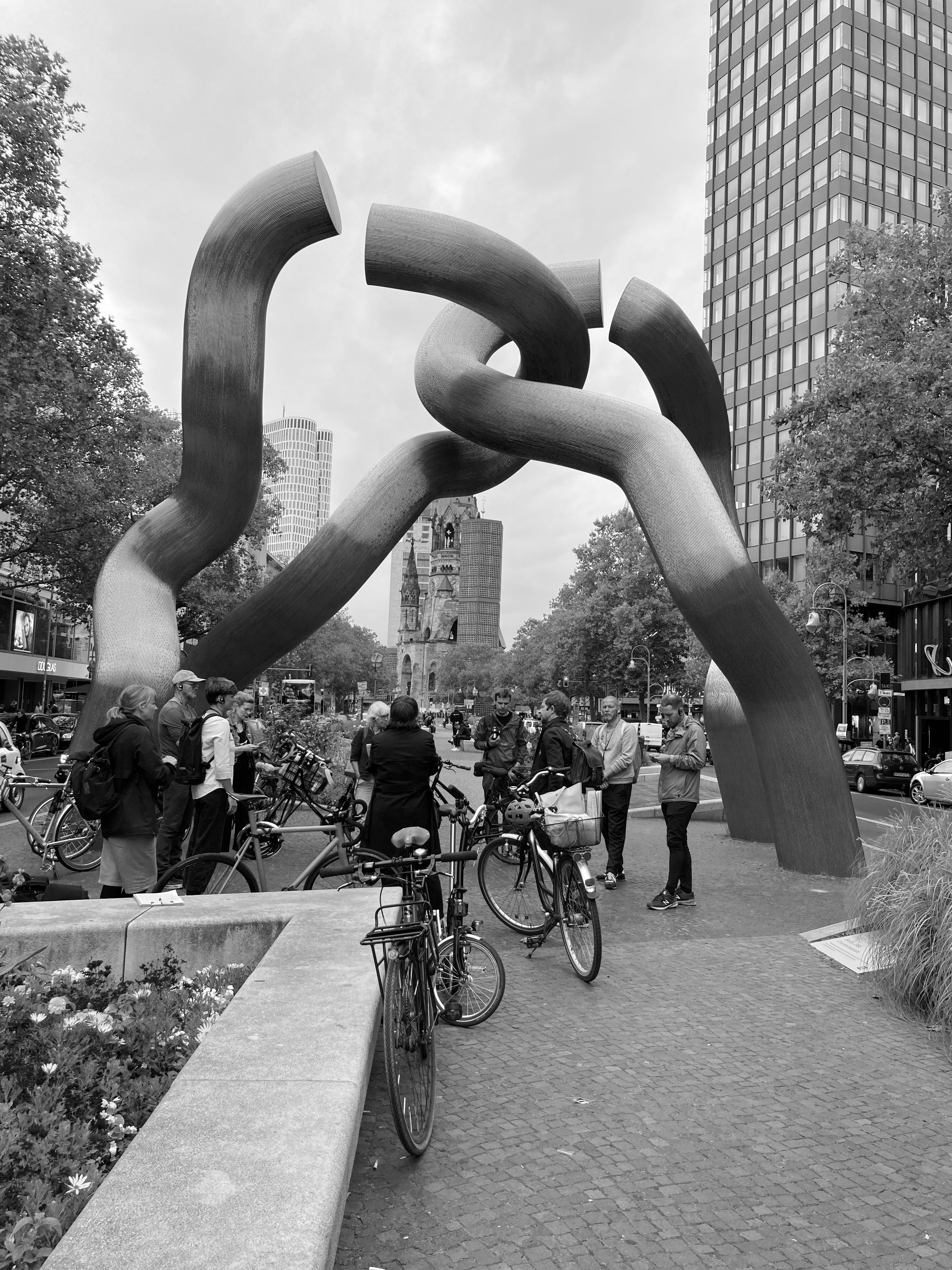 Torartige Skulptur auf dem Mittelstreifen der Tauentzienstraße. Darunter versammeln sich Mitglieder des Reallabor Radbahn und des Projektbeirats.