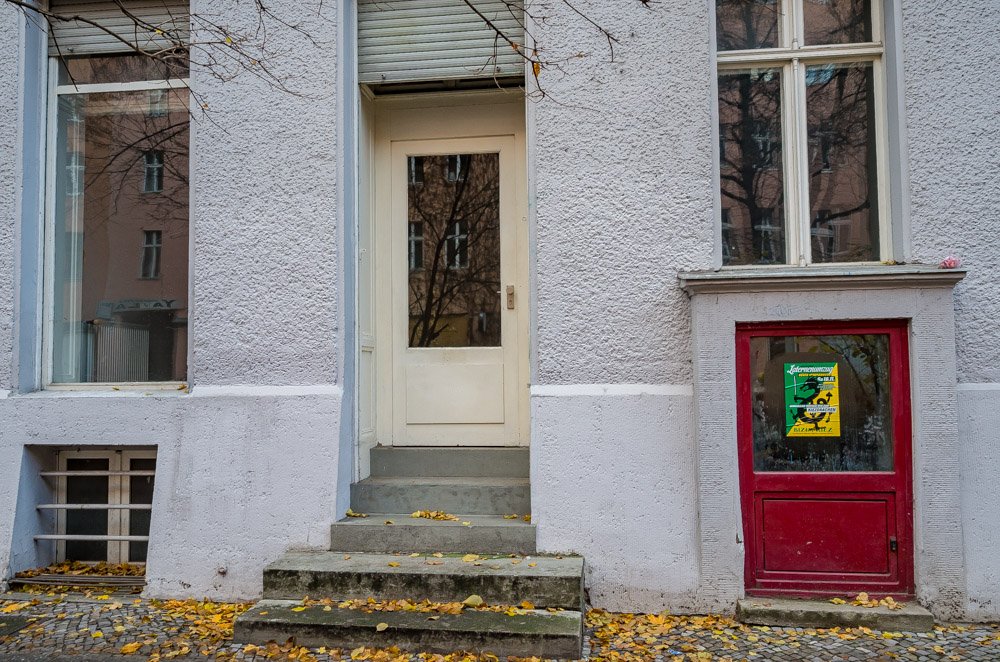 Foto des Büro vons Reallabor Radbahn. Außenansicht des Hauses und frontale Darstellung des Ladengeschäfts. Eine Tür in der Mitte zu der drei Stufen hochführen und daneben jeweils ein Fenster.